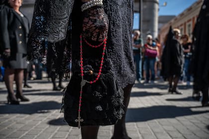 Una mujer con ropa tradicional de Pascua es vista llevando un rosario durante la procesión de la Soledad del Sábado de Pascua