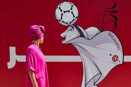 Una mujer con turbante mira una imagen de La’eeb, la mascota oficial de la Copa Mundial de la FIFA Qatar 2022