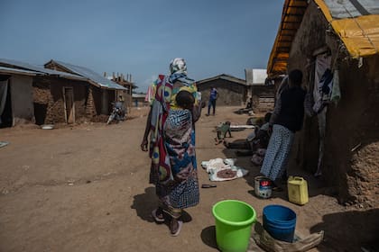 Una mujer con un niño a la espalda camina por un campamento en una propiedad del ISP (Institut Supérieur Pédagogique) de la ciudad, donde residen desplazados internos, en Bunia, República Democrática de Congo, el 26 de mayo de 2026. (AP Foto/Moses Sawasawa)