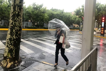 Una mujer con un paraguas se protege del viento y la lluvia