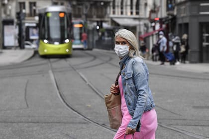 Una mujer con una mascarilla como medida contra la propagación de la pandemia de coronavirus, camina el 22 de octubre de 2020 en una calle de Saint-Etienne, en Francia