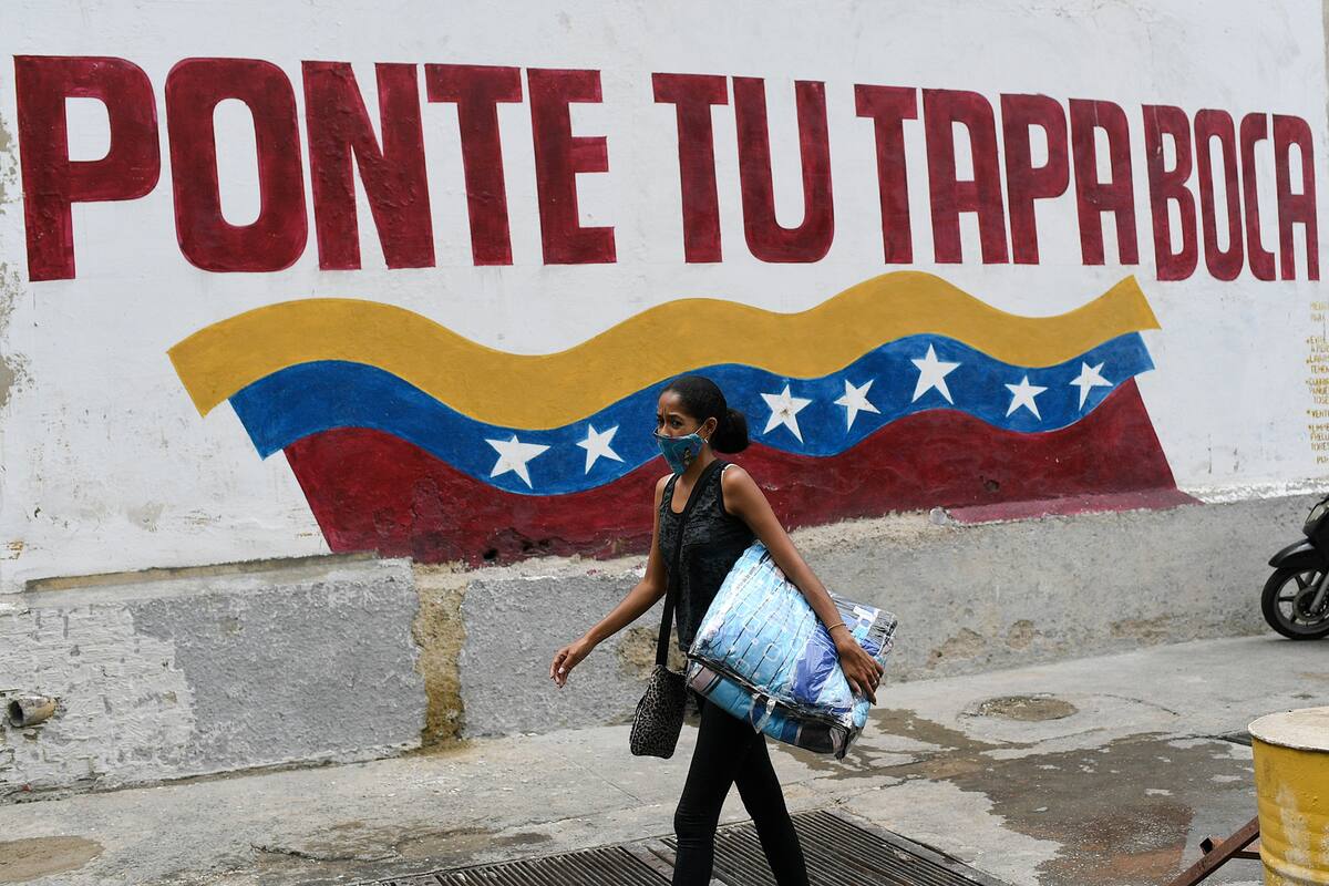 Una mujer con una mascarilla protectora pasa junto a un mural con un mensaje que dice en español: "Ponte la mascarilla" en el barrio Catia de Caracas, Venezuela, el sábado 5 de septiembre de 2020, en medio de la nueva pandemia de coronavirus.