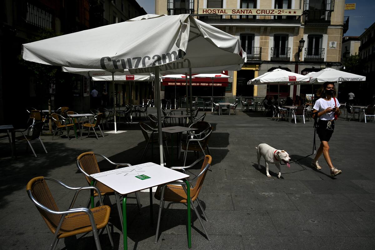 Una mujer cono tapabocas pasea a su perro por la terraza de un restaurante vacío en el centro de Madrid el 16 de septiembre de 2020