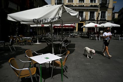 Una mujer cono tapabocas pasea a su perro por la terraza de un restaurante vacío en el centro de Madrid el 16 de septiembre de 2020