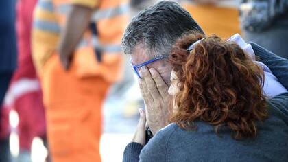 Una mujer consuela a su marido mientras los bomberos recuperan el cuerpo sin vida de su madre entre los escombros de un edificio en Amatrice