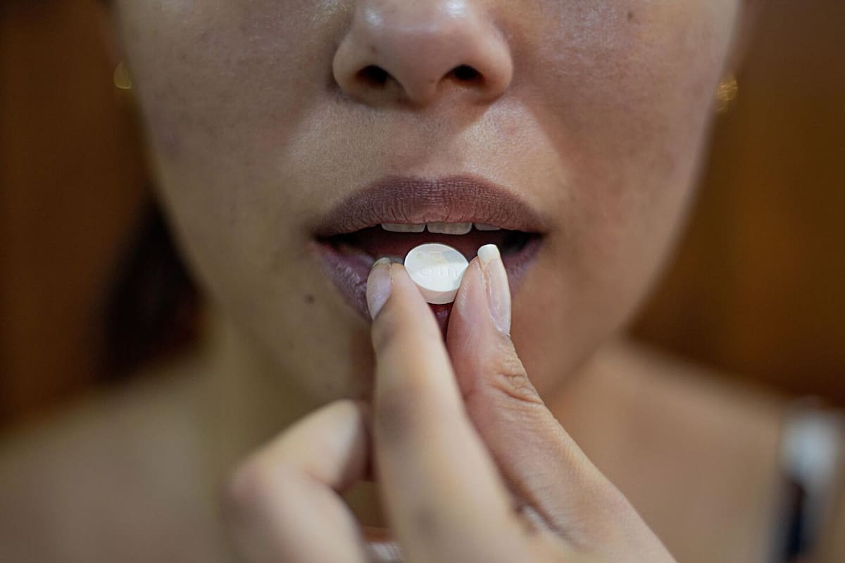 Una mujer consumiendo una pastilla blanca.Foto: danilo.alvesd / Unsplash