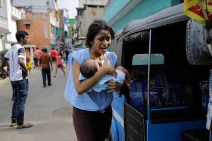 Una mujer corre en Colombo con su hijo luego de que la policía encontró explosivos en un auto estacionado