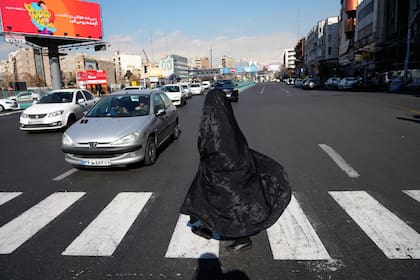 Una mujer cruza en una calle en el centro de Teherán, el viernes 16 de enero