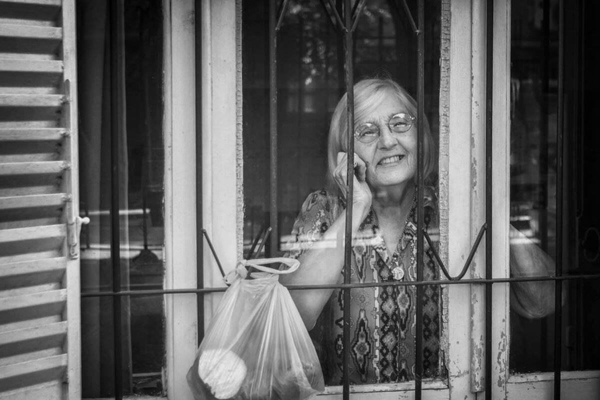 Una mujer de Mercedes, en la provincia de Buenos Aires, recibe en su ventana las compras realizadas por un grupo de voluntarios abocados a asistir a las personas mayores afectadas por las medidas de aislamiento