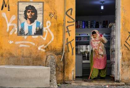Una mujer de pie junto a un mural dedicado a Diego Armando Maradona, del artista callejero Harry Greb, distrito de Trastevere de Roma