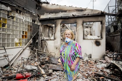 Una mujer del pueblo costero de Mati, frente a su casa destrozada por los incendios forestales