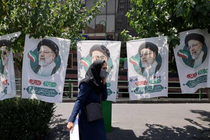 Una mujer en Teherán camina frente a los posters del candidato conservador Ebrahim Raisi