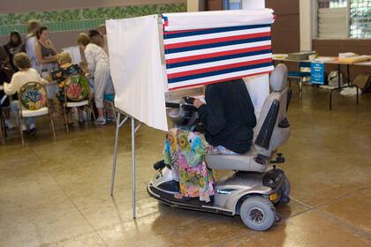 Una mujer en una silla de ruedas motorizada deposita su voto en Honolulu, el 4 de noviembre del 2008. (AP foto/Marco Garcia)