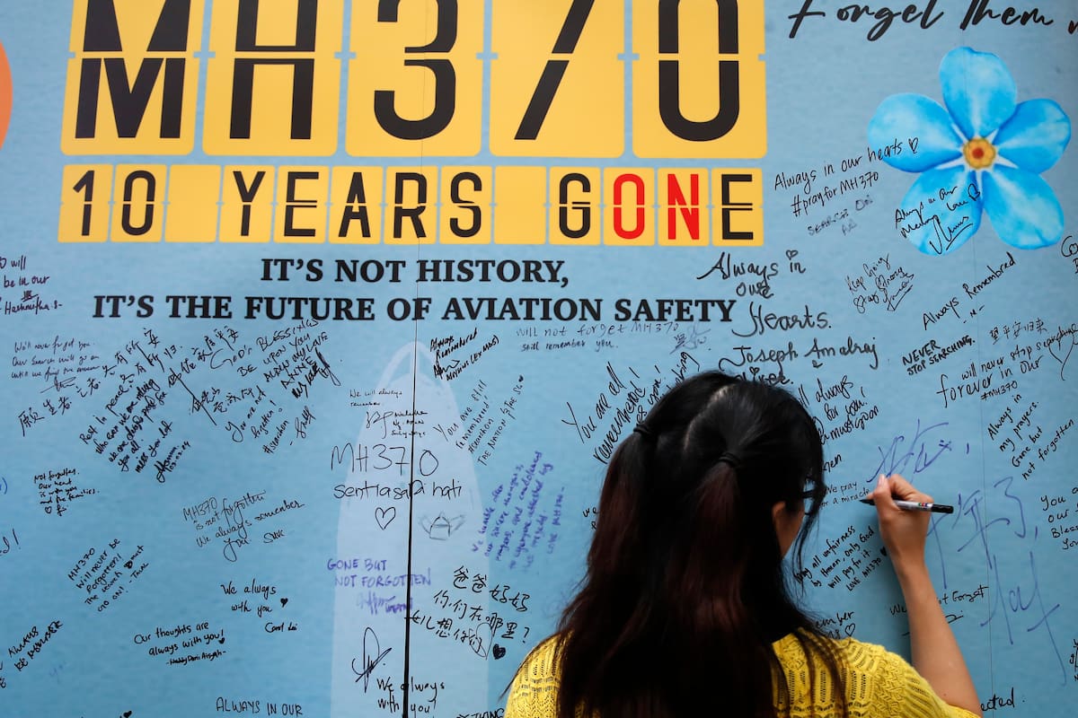 Una mujer escribe un mensaje en un panel durante un acto para conmemorar los 10 años de la desaparición del vuelo MH370 de Malaysia Airlines, en un centro comercial en Subang Jaya, en las afueras de Kuala Lumpur, Malasia
