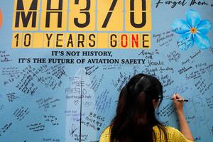 Una mujer escribe un mensaje en un panel durante un acto para conmemorar los 10 años de la desaparición del vuelo MH370 de Malaysia Airlines, en un centro comercial en Subang Jaya, en las afueras de Kuala Lumpur, Malasia