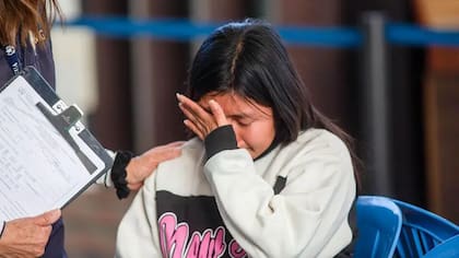 Una mujer guatemalteca deportada llora mientras habla con un agente del Instituto Guatemalteco de Migración en el centro de inmigración, tras llegar al Aeropuerto Internacional La Aurora luego de su deportación desde los Estados Unidos