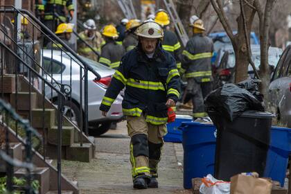 Una mujer habla por teléfono en el sitio donde ocurrió un incendio en el vecindario de Fairmount, el miércoles 5 de enero de 2022, en Filadelfia. (Monica Herndon/The Philadelphia Inquirer vía AP)