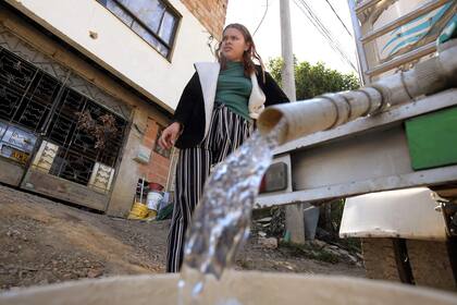 Una mujer junta agua potable de un camión cisterna en La Calera, cerca de Bogotá, el 10 de abril de 2024.