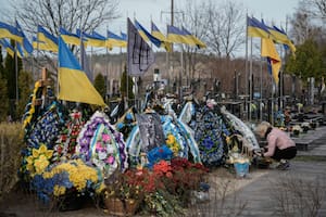 Una mujer limpia la tumba de un familiar muerto en combate, en el cementerio de Bucha, en las afueras de Kiev, el sábado 30 de marzo de 2024. (AP Foto/Enric Marti)