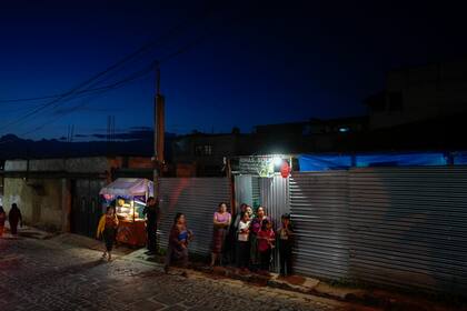 Una mujer llega a un centro de votación para votar con una niña en brazos durante la segunda vuelta de las elecciones presidenciales en Santa María Cauque, Guatemala, el domingo 20 de agosto de 2023. (Foto AP/Moisés Castillo)