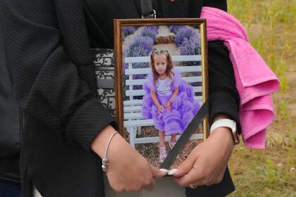 Una mujer lleva un retrato de Liza, una niña de 4 años muerta por un ataque ruso, durante su funeral en Vinnytsia, Ucrania, el domingo 17 de julio de 2022. (Foto AP/Efrem Lukatsky)