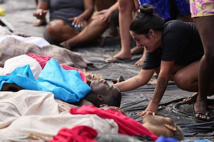 Una mujer llora junto a los cuerpos de personas abatidas