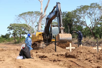 Una mujer llora mientras espera que el tractor termine de hacer la fosa para enterrar a su familiar en un cementerio improvisado para víctimas de Covid19. Crédito: Ricardo Gutiérrez