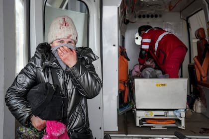 Una mujer llora mientras los paramédicos intentan hacer reaccionar a una chica herida en un ataque ruso en Mariupol
