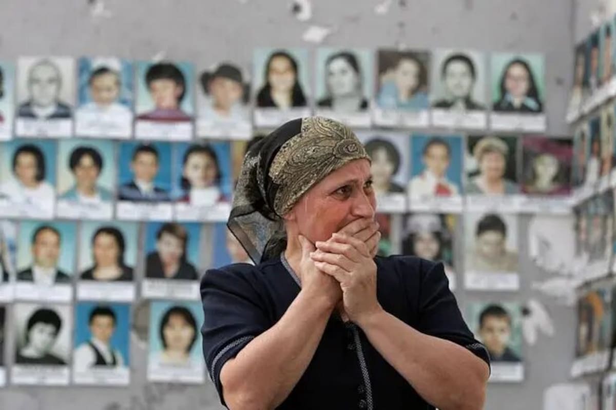 Una mujer llora mientras mira las fotos de las víctimas asesinadas en el polideportivo escolar de Beslán