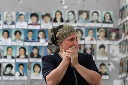 Una mujer llora mientras mira las fotos de las víctimas asesinadas en el polideportivo escolar de Beslán