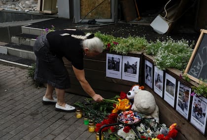 Una mujer local coloca flores en el altar improvisado ante la pizzería RIA, atacada por un cohete ruso en Kramatorsk, en la región de Donetsk, Ucrania, el jueves 29 de junio de 2023. (AP Foto/Alex Babenko)