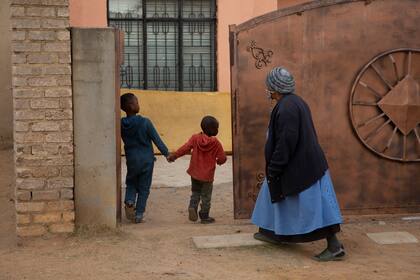 Una mujer mayor y dos niños entran a la casa de Gosiame Thamara Sithole en Tembisa, cerca de Johannesburgo, el jueves 10 de junio de 2021. (AP Foto/Denis Farrell)
