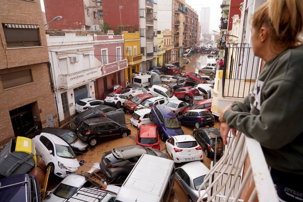Una mujer mira por su balcón a los vehículos atrapados en la calle durante la inundación en Valencia