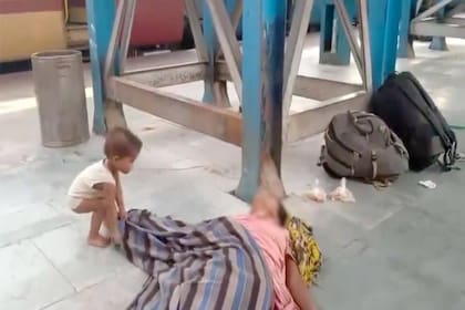 Una mujer muere en el andén de trenes en India y su hijo se pone a jugar con ella