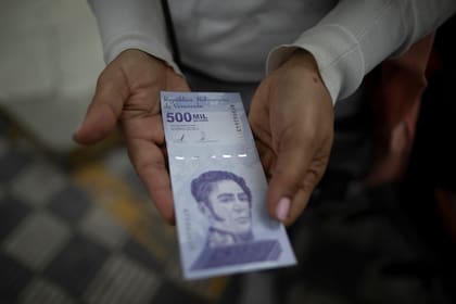Una mujer muestra un nuevo billete de 500.000 bolívares luego de retirarlo de un banco en Caracas, Venezuela. (AP Foto/Ariana Cubillos, Archivo)