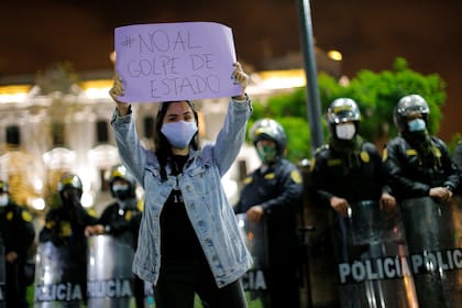 Una mujer muestra un cartel que dice "No al golpe de Estado", durante una protesta en una plaza principal de Lima tras el anuncio de la destitución del presidente peruano Martín Vizcarra