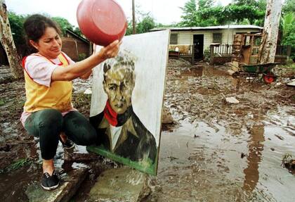 Una mujer nicaragüense limpia de barro el retrato de Sandino tras sufrir los estragos del huracán Mitch en 1998.