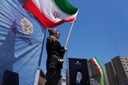 Una mujer ondea una bandera iraní durante una marcha progobierno, en Teherán