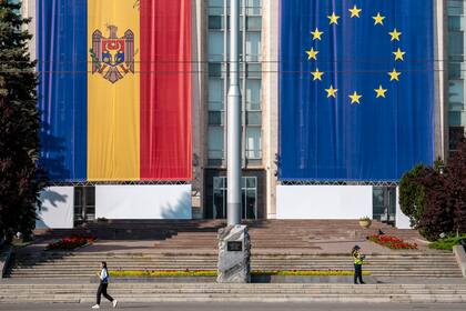 Una mujer pasa junto a un edificio gubernamental decorado con banderas de Moldavia y la Unión Europea en Chisinau, Moldavia, el 31 de mayo de 2023.