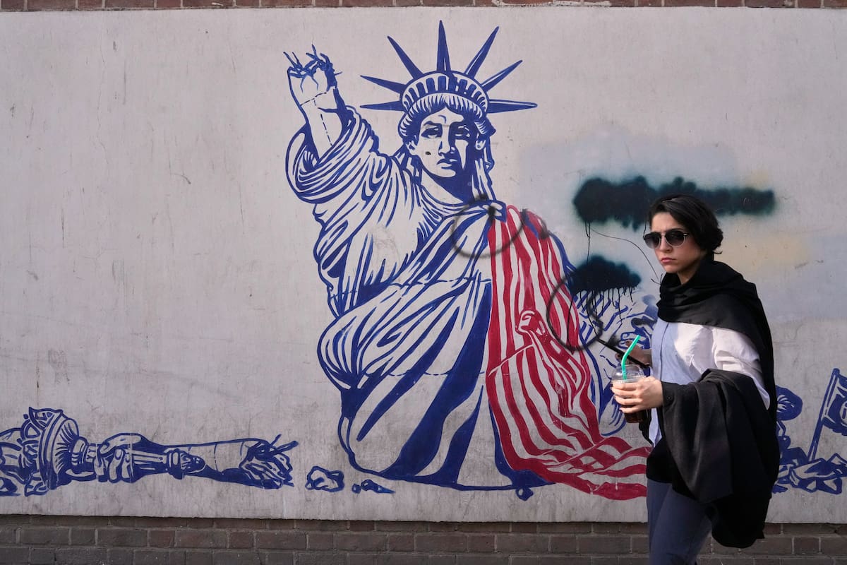 Una mujer pasa junto a un mural antiestadounidense en la pared de la antigua embajada de Estados Unidos, ahora convertida en museo, en Teherán