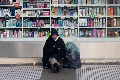 Una mujer pide dinero en el exterior de una farmacia de Buenos Aires