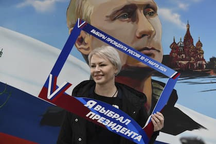 Una mujer posa con un cartel que dice "Yo elegí al presidente" luego de votar en Donetsk, región ucraniana bajo control ruso. (AP)