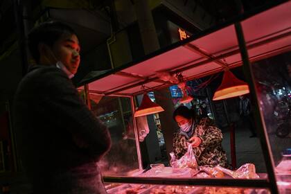 Una mujer que usa una mascarilla como medida preventiva contra el Covid-19 vende comida en una calle de Wuhan, provincia de Hubei, en el centro de China, el 18 de enero de 2021