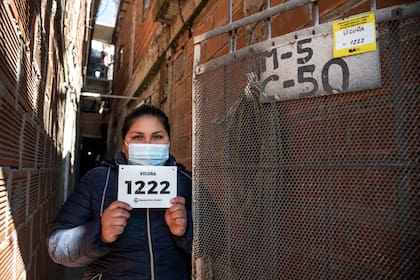 Una mujer residente en la villa 31 muestra el cartel de denominación de la calle y el número donde se ubica su vivienda