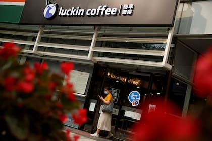Una mujer sale de una tienda de la cadena de cafés chinos Luckin Coffee en Beijing, China