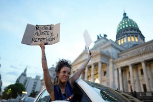 Una mujer se asoma por la ventana de un vehículo sosteniendo carteles de rechazo a la reforma económica promovida por el presidente argentino, Javier Milei, a su paso por el Congreso en Buenos Aires, Argentina, el martes 6 de febrero de 2024. La Cámara de Diputados tiene en debate el proyecto de ley que incluye una variedad de medidas económicas, administrativas, penales y medioambientales. (AP Foto/Natacha Pisarenko)