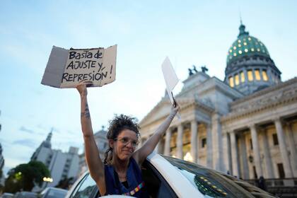 Una mujer se asoma por la ventana de un vehículo sosteniendo carteles de rechazo a la reforma económica promovida por el presidente argentino, Javier Milei, a su paso por el Congreso en Buenos Aires, Argentina, el martes 6 de febrero de 2024. La Cámara de Diputados tiene en debate el proyecto de ley que incluye una variedad de medidas económicas, administrativas, penales y medioambientales. (AP Foto/Natacha Pisarenko)