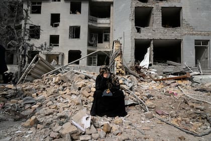 Una mujer se sienta sobre los escombros frente a un edificio residencial dañado el domingo durante la campaña aérea de Estados Unidos e Israel en Teherán, Irán