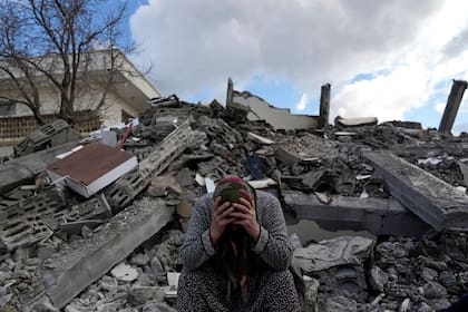 Una mujer sentada sobre los escombros de un edificio que se derrumbó por el sismo del lunes en Nurdagi, sur de Turquía, el martes 7 de febrero de 2023. (AP Foto/Khalil Hamra)