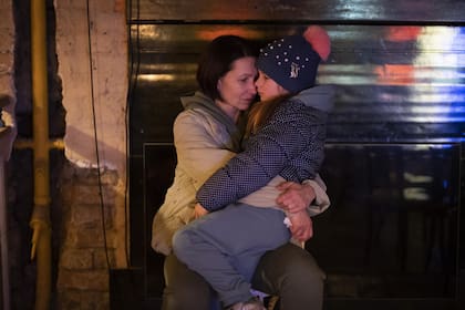Una mujer sostiene a su hija sentada en un sótano utilizado como refugio antiaéreo en Kiev, Ucrania